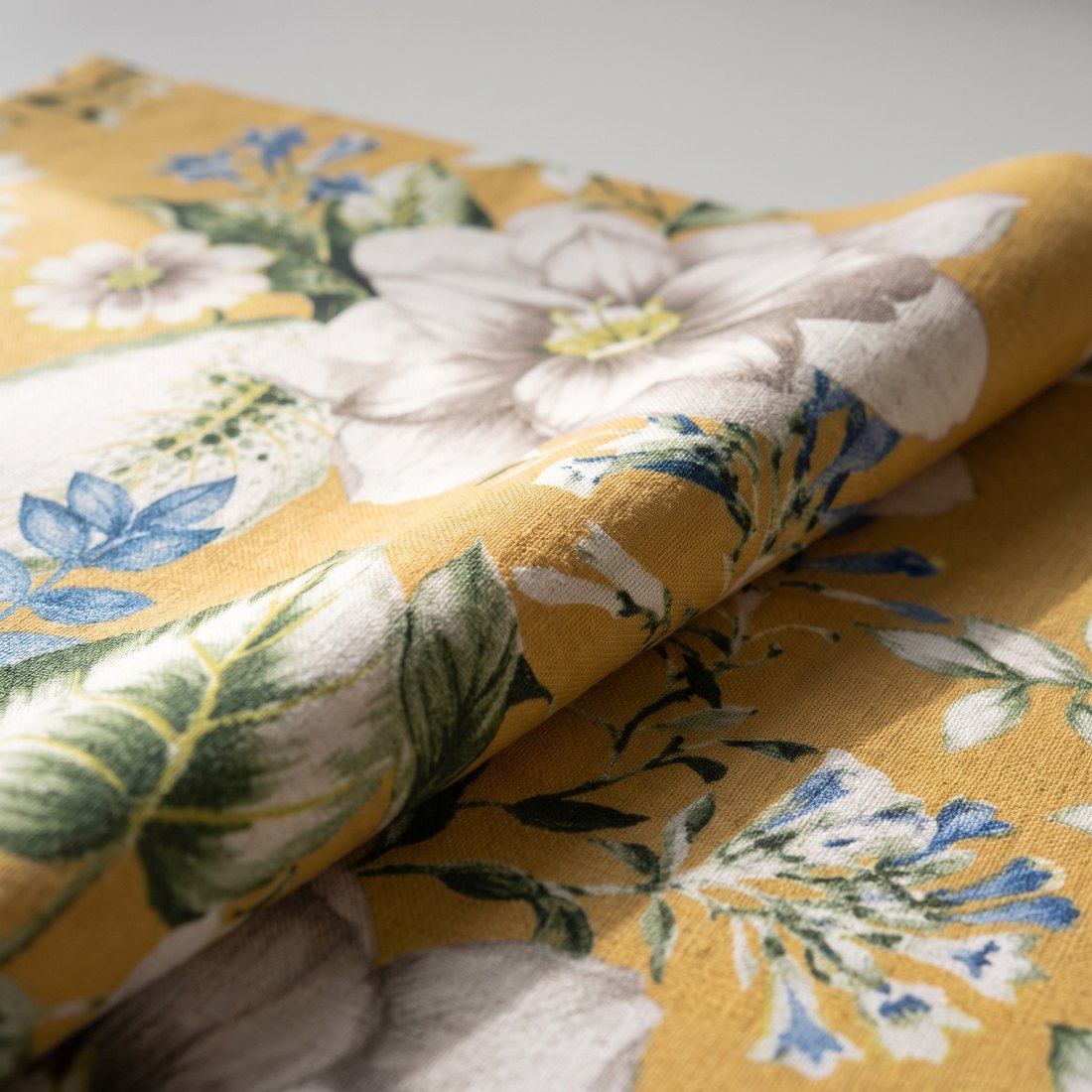 Tissu botanique sur fond ocre : lys blancs et feuillage.